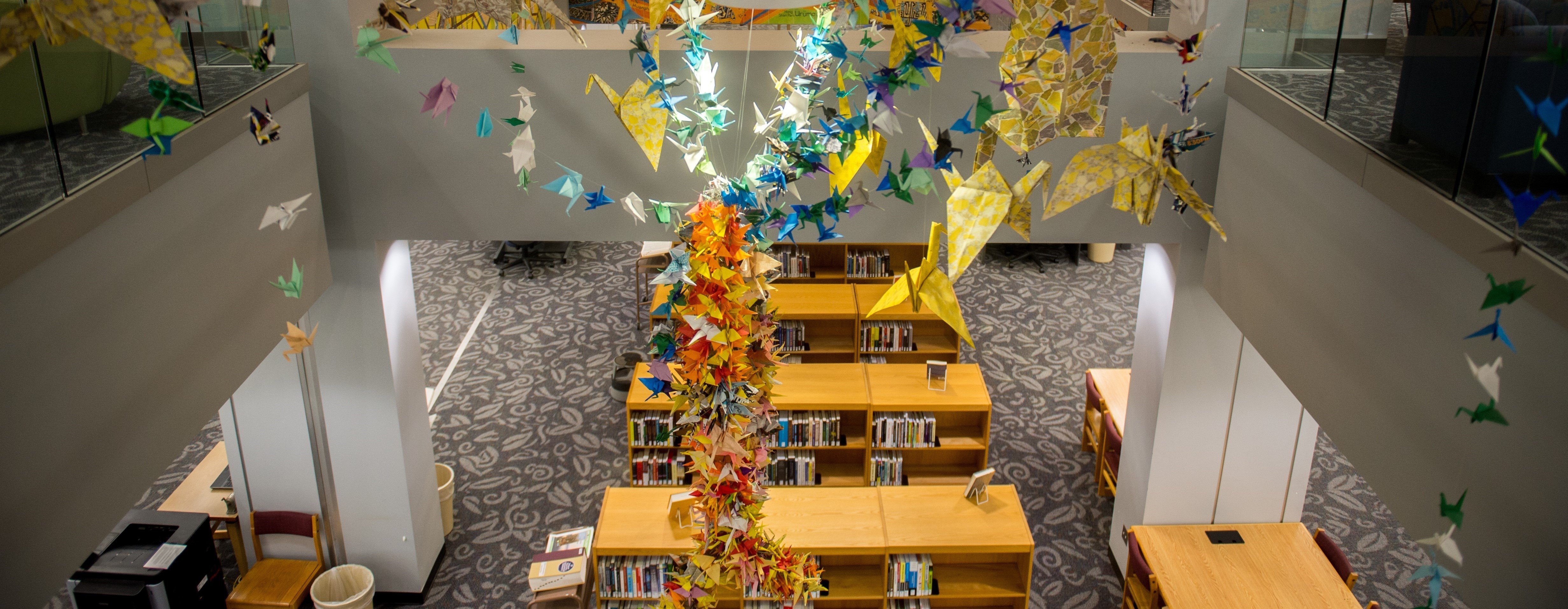 a group of paper birds from a ceiling in a library