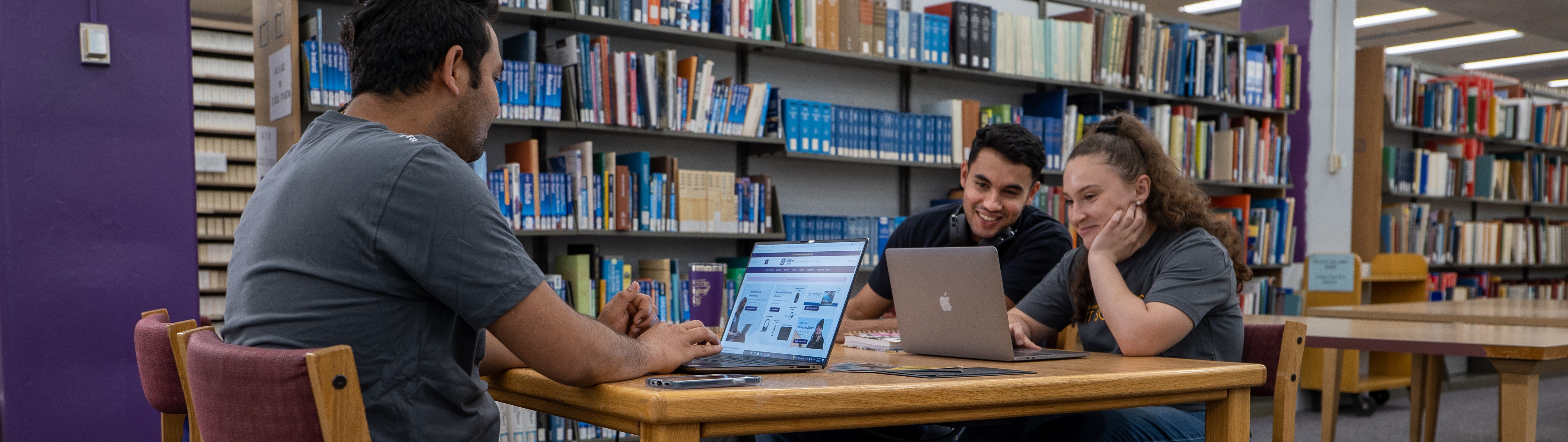 a person sitting at a table with a laptop and another person sitting at a table